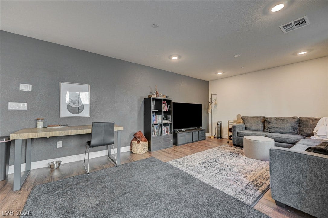 Recessed lighting highlights the rich wood flooring in this versatile living space.