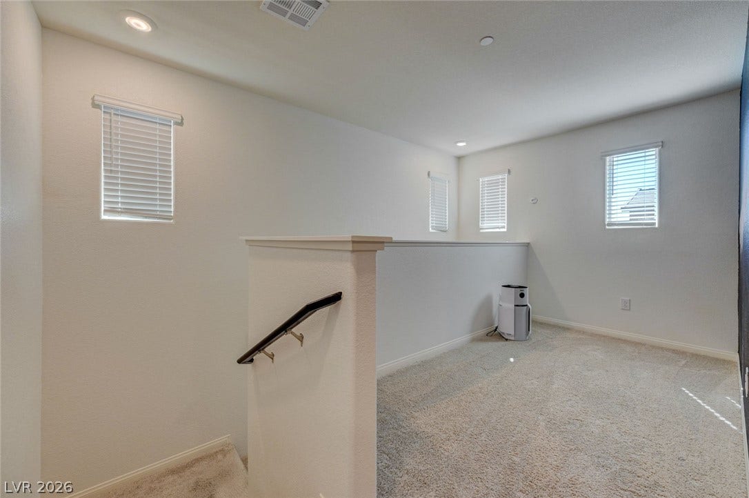 A versatile upper-level loft area boasts plush carpeting, recessed lighting, and multiple windows.