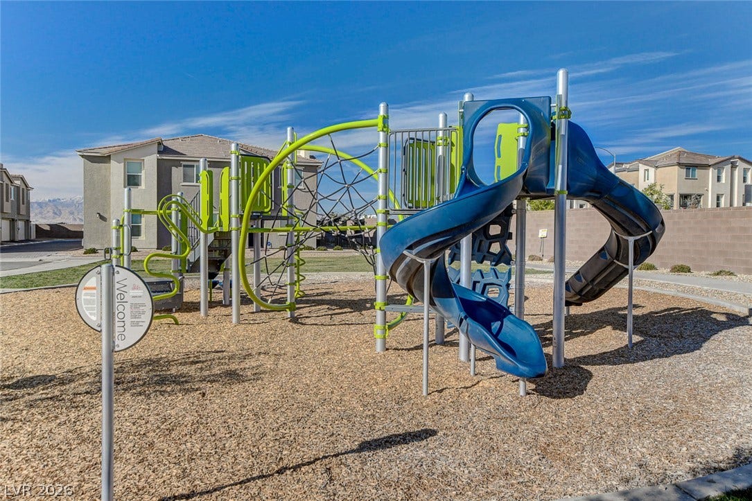 An on-site playground area rests over wood chips beneath a clear blue sky.