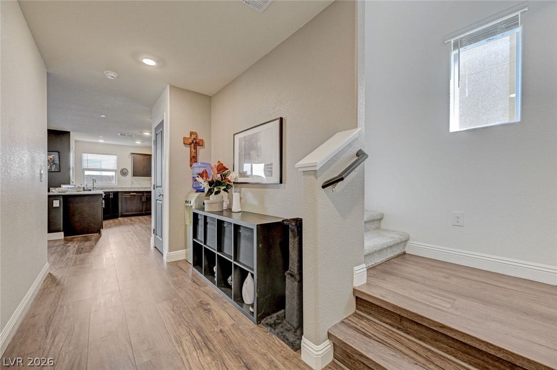 Warm wood-look flooring guides the eye through an open-concept hallway toward the kitchen.