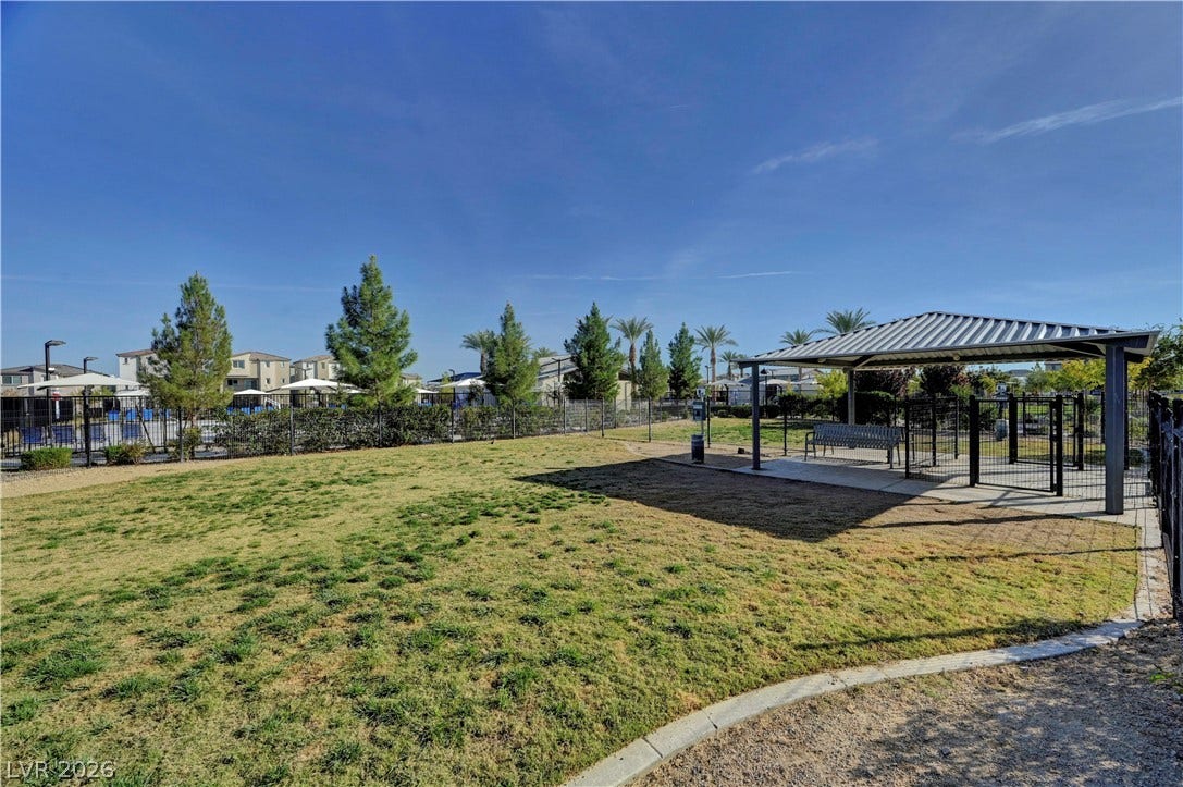 Fenced community green space features a covered pavilion amidst manicured grassy lawns.