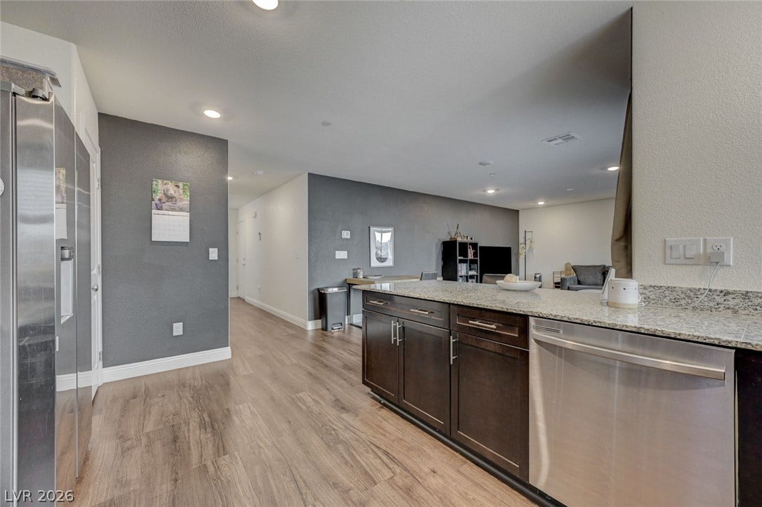 Gleaming wood-look floors complement stone countertops in this modern open layout.