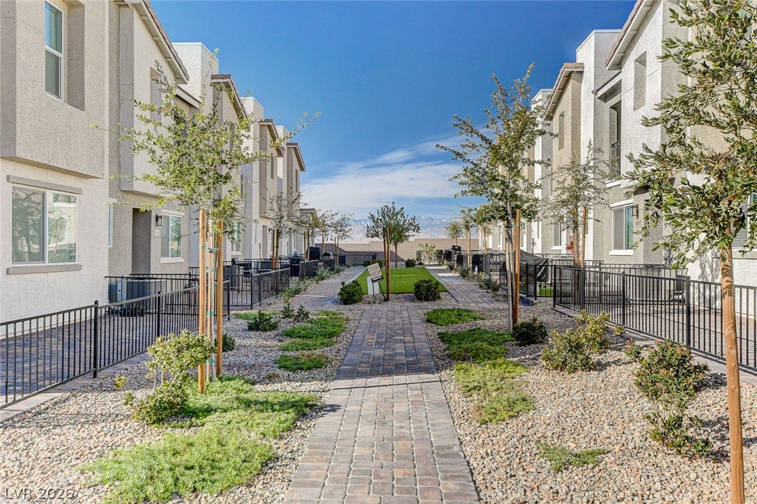 A paved walkway winds through meticulously landscaped common areas nestled between modern residential buildings.