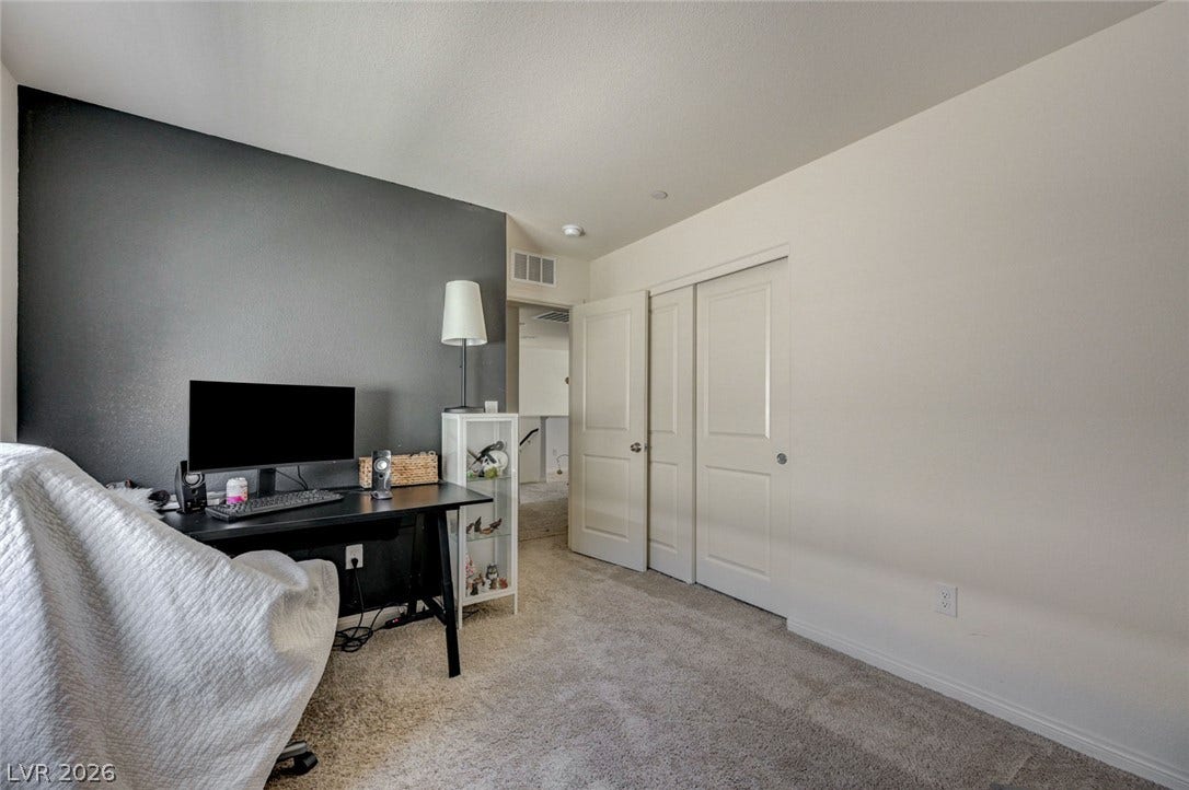 Soft carpeting pairs with smooth neutral walls in this versatile secondary bedroom space.