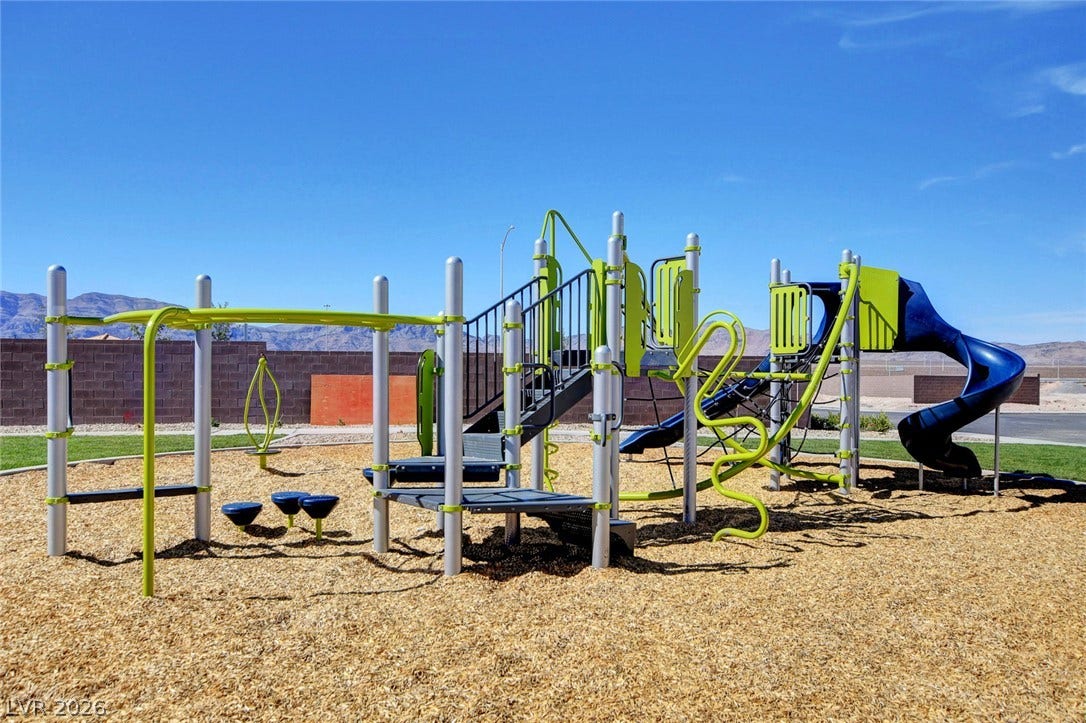 An expansive outdoor play area sits beneath clear blue skies with scenic mountain backdrops.