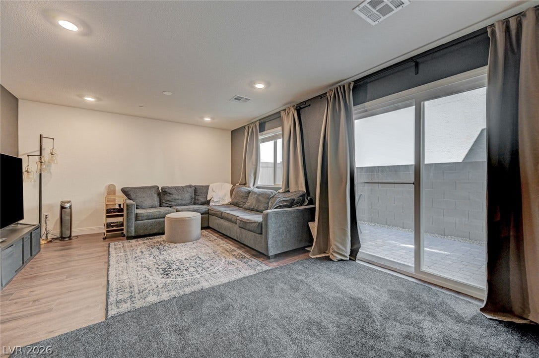 Sliding glass doors open from this versatile space onto a private paved patio.