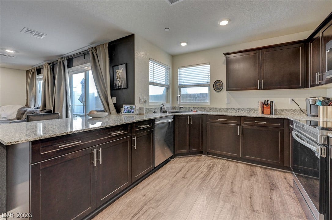 Rich dark cabinetry and stone countertops anchor this modern kitchen with warm wood flooring.