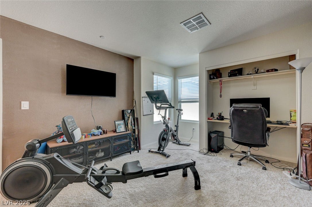 A versatile secondary room provides soft carpeting alongside a dedicated desk nook and bright windows.