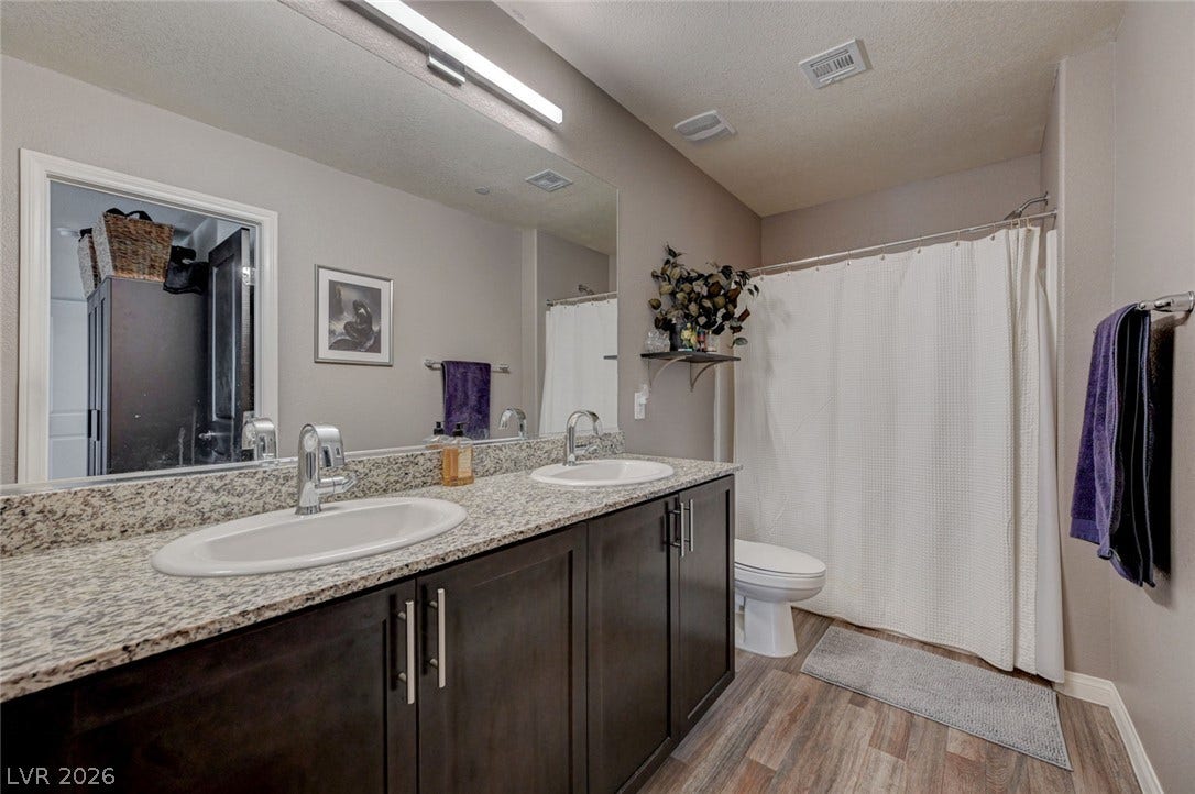 Polished stone counters elevate this modern bathroom featuring durable wood-look flooring.