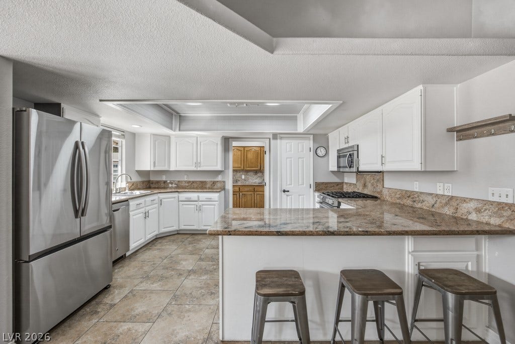 251 W Laval Drive, Henderson, NV 89015 Generous kitchen features an expansive breakfast bar with seating, granite countertops, stainless steel appliances, ample cabinetry, large pantry, and an open connection to the dining area.