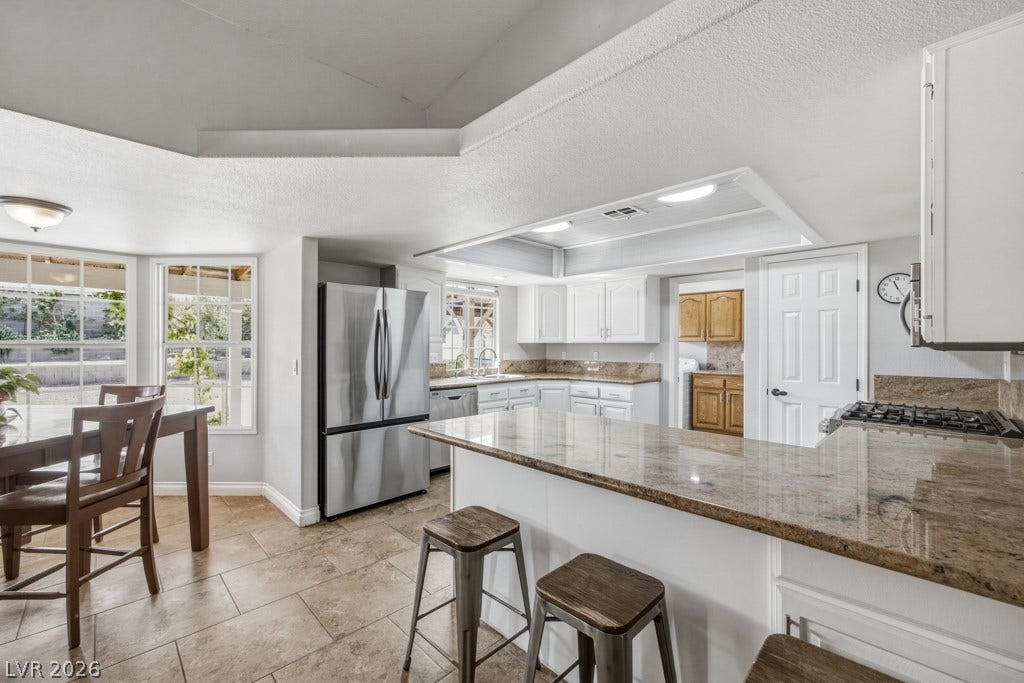 251 W Laval Drive, Henderson, NV 89015 Generous kitchen features an expansive breakfast bar with seating, granite countertops, stainless steel appliances, ample cabinetry, large pantry, and an open connection to the dining area.