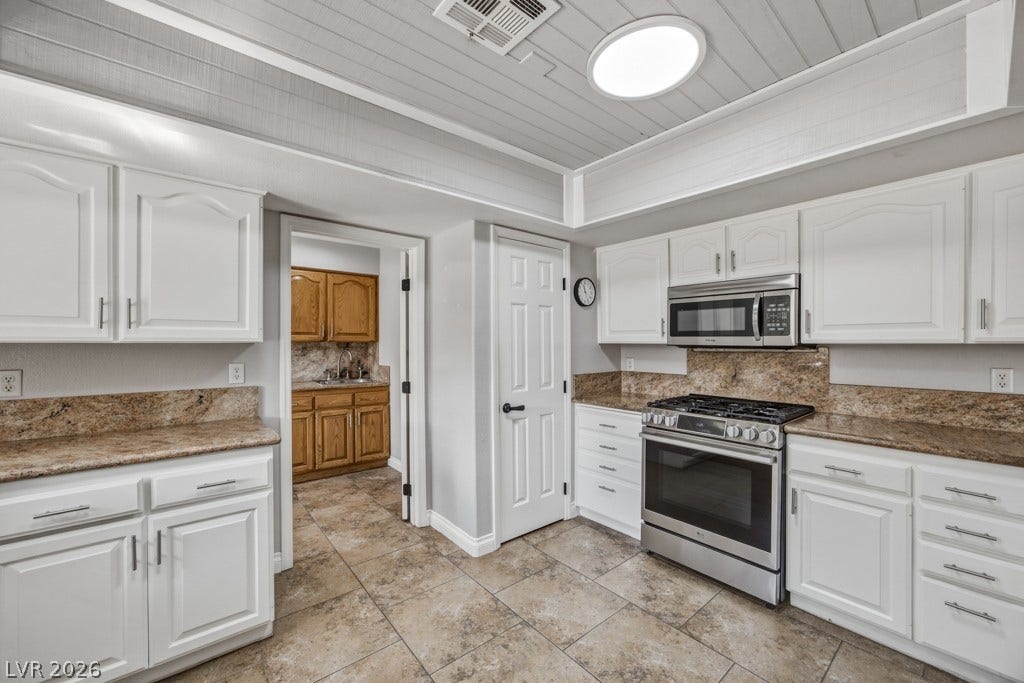 251 W Laval Drive, Henderson, NV 89015 Generous kitchen features an expansive breakfast bar with seating, granite countertops, stainless steel appliances, ample cabinetry, large pantry, and an open connection to the dining area.