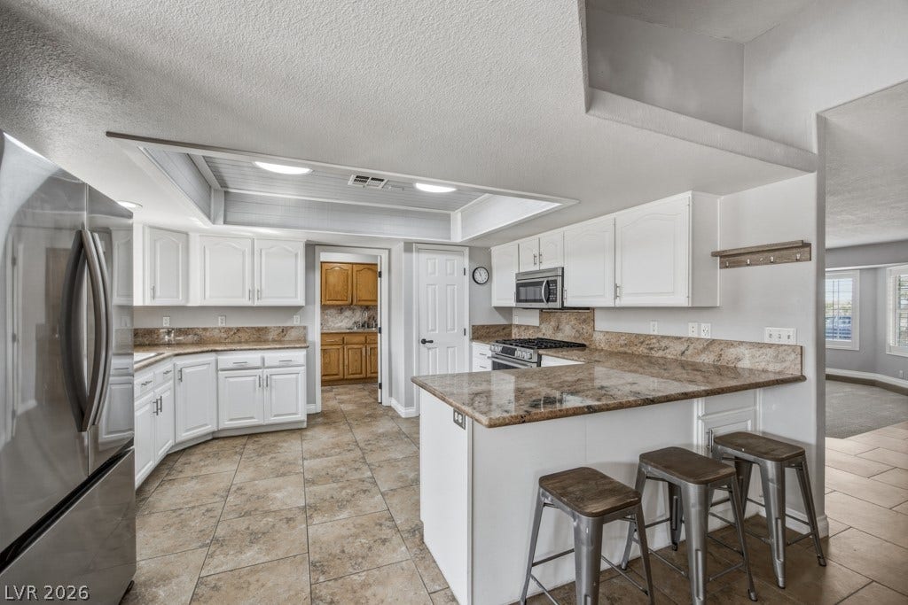 251 W Laval Drive, Henderson, NV 89015 Generous kitchen features an expansive breakfast bar with seating, granite countertops, stainless steel appliances, ample cabinetry, large pantry, and an open connection to the dining area.