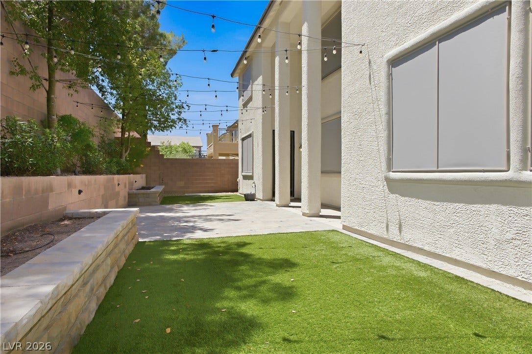 Back Yard with synthetic grass, pavers, and mature shrubs and trees.
