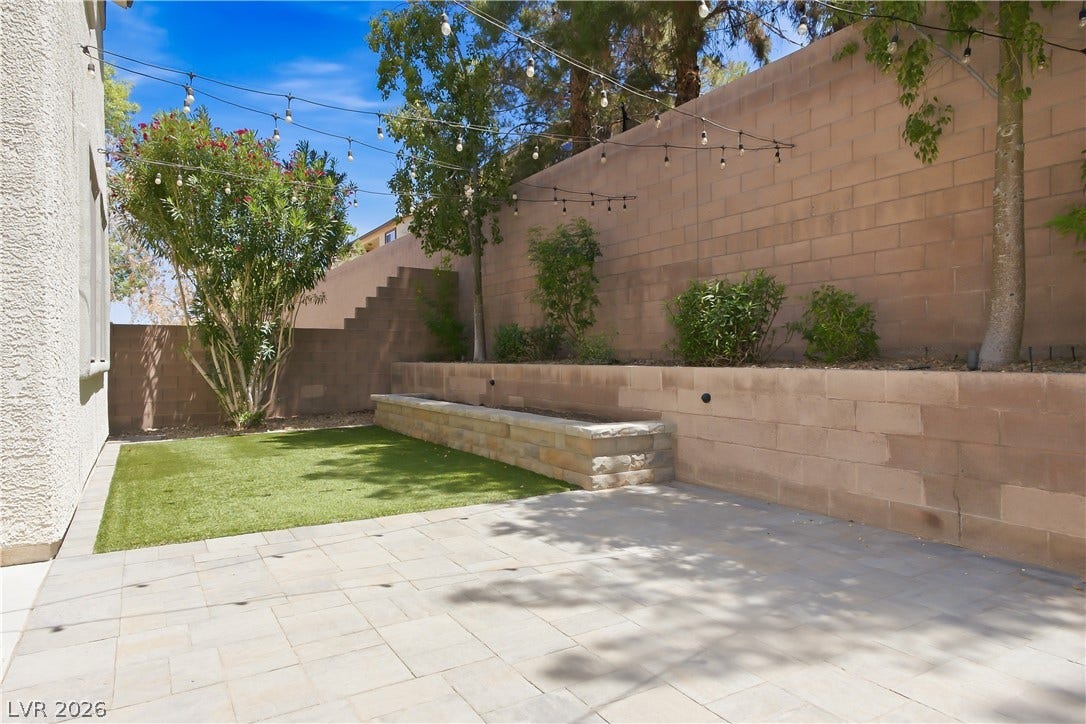 Back Yard with synthetic grass, pavers, and mature shrubs and trees.