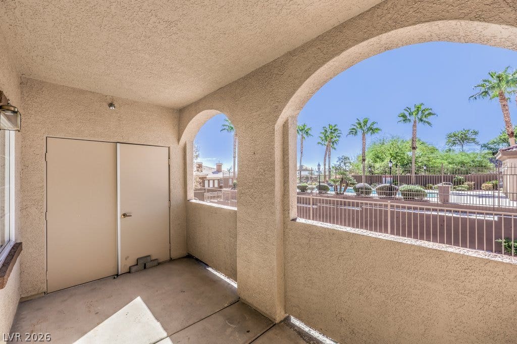 3910 Legend Hills Street, #103, Las Vegas, NV 89129 An arched stucco veranda overlooks a serene community pool lined with palm trees.