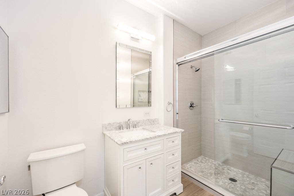 3910 Legend Hills Street, #103, Las Vegas, NV 89129 A stone-topped vanity and a glass-enclosed shower with tiled walls define this modern bathroom.