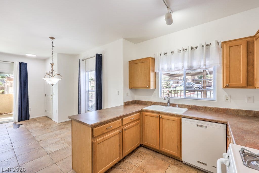 3910 Legend Hills Street, #103, Las Vegas, NV 89129 Warm wood cabinetry and tile flooring anchor this functional, light-filled kitchen space.