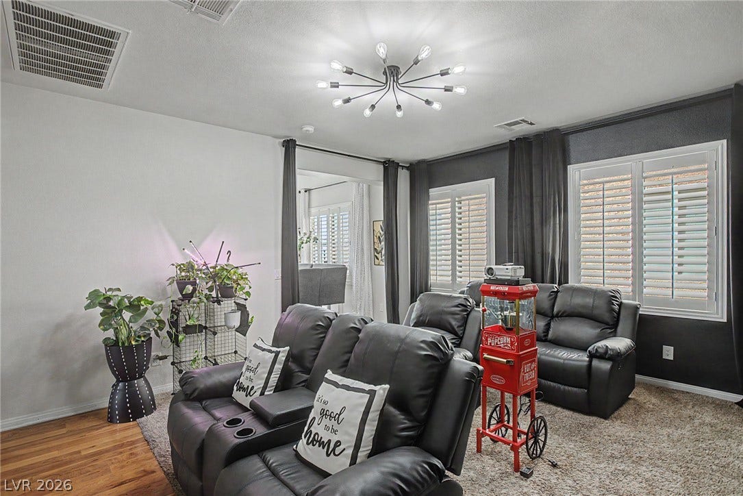 6025 Glenborough Street, North Las Vegas, NV 89115 Gleaming hardwood floors border a cozy carpeted area illuminated by modern overhead lighting.