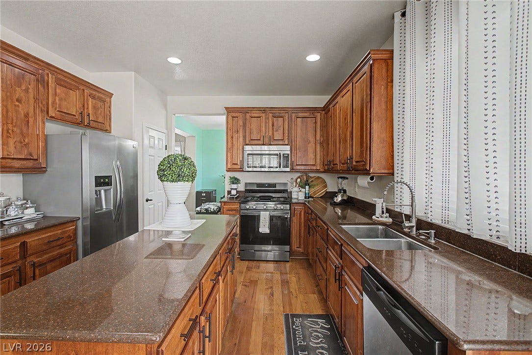 6025 Glenborough Street, North Las Vegas, NV 89115 Rich wood cabinetry and stone countertops anchor this classic kitchen with a central island.