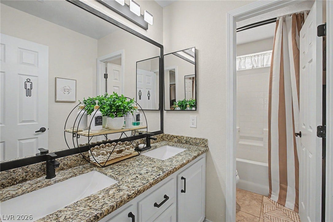 6025 Glenborough Street, North Las Vegas, NV 89115 Granite countertops paired with white cabinetry anchor this functional bathroom space.
