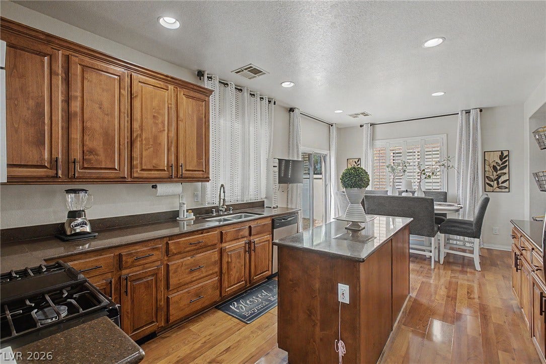 6025 Glenborough Street, North Las Vegas, NV 89115 Gleaming hardwood floors run through this open kitchen featuring wooden cabinetry and a central island.