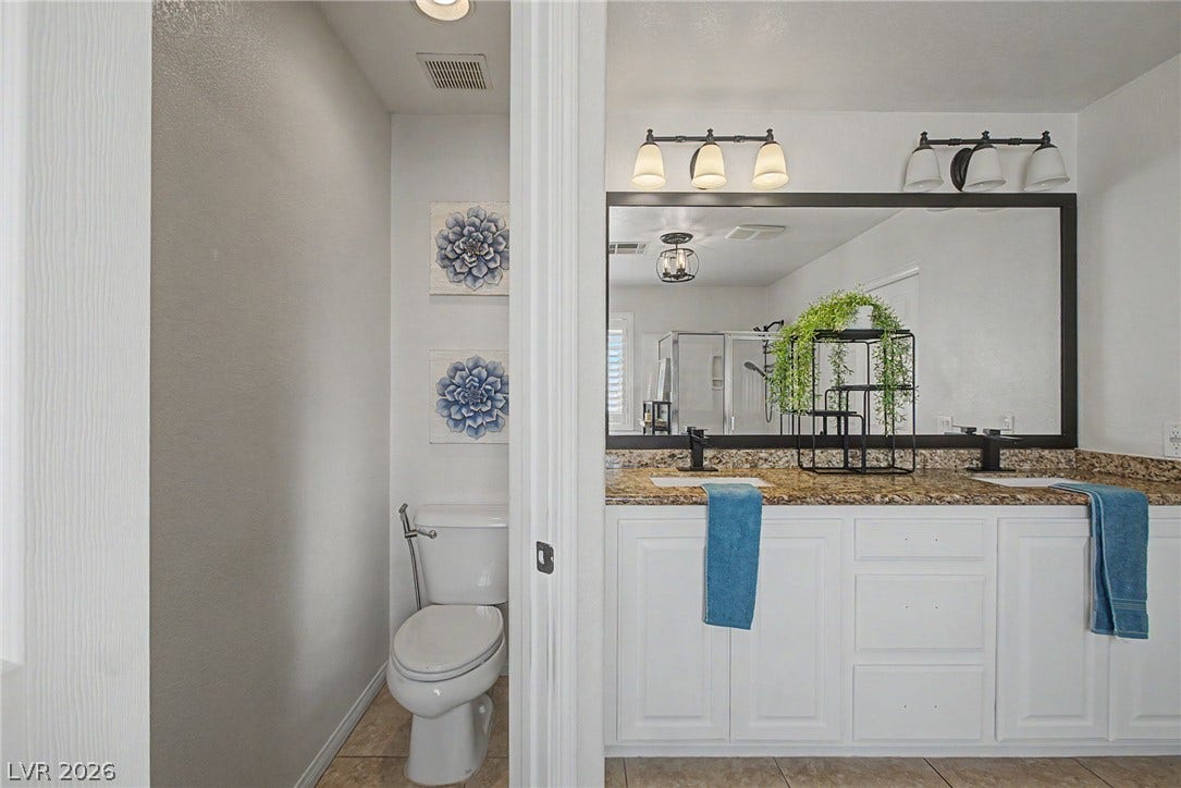6025 Glenborough Street, North Las Vegas, NV 89115 Granite counters and a wide double vanity elevate this modern bathroom layout.