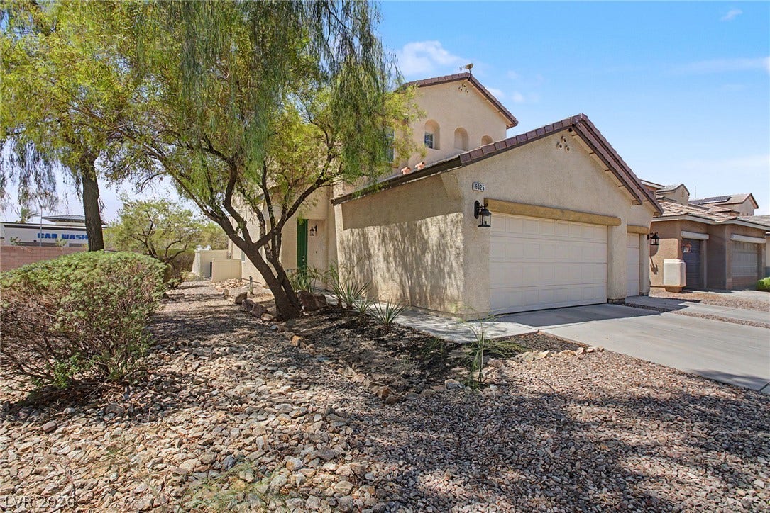6025 Glenborough Street, North Las Vegas, NV 89115 Desert landscaping and mature trees frame the stucco exterior of this multi-level home.