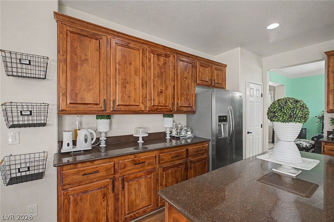 6025 Glenborough Street, North Las Vegas, NV 89115 Rich wood cabinetry and polished stone countertops elevate this spacious kitchen layout.