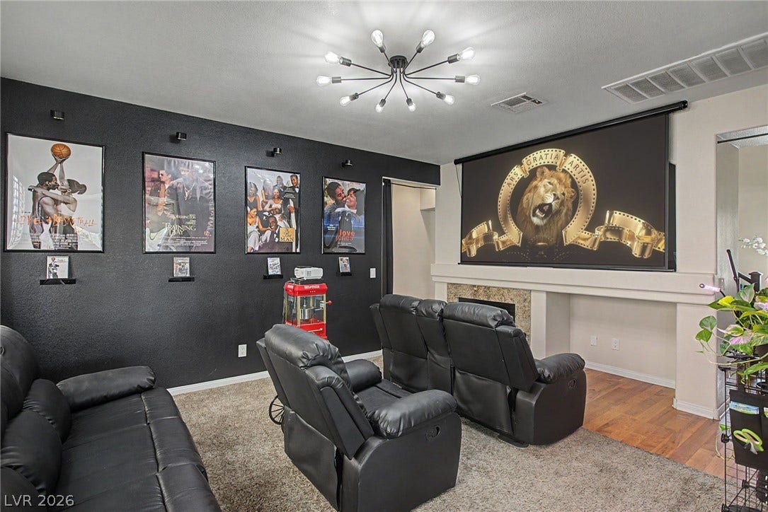6025 Glenborough Street, North Las Vegas, NV 89115 A dedicated home theater room showcases dark walls and a large projection screen above the fireplace.