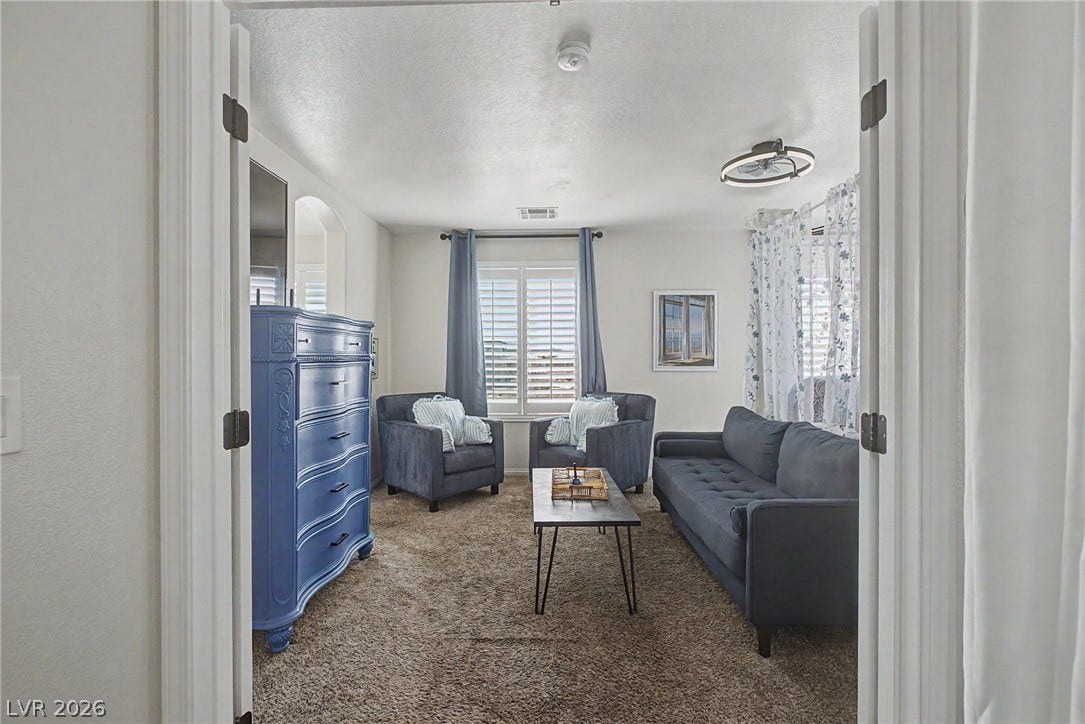 6025 Glenborough Street, North Las Vegas, NV 89115 Double doors open to a comfortable living area with carpeted floors and bright windows.
