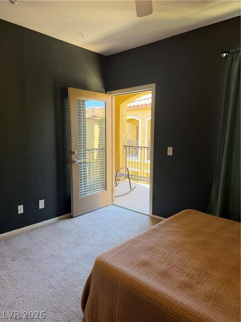 Plush carpeting and an open glass door leading to a private outdoor balcony.