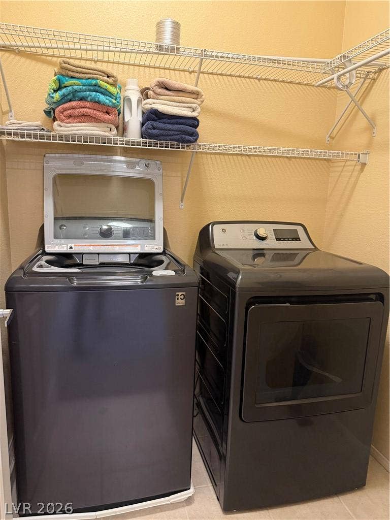 Functional utility space features overhead wire shelving and modern laundry appliances.