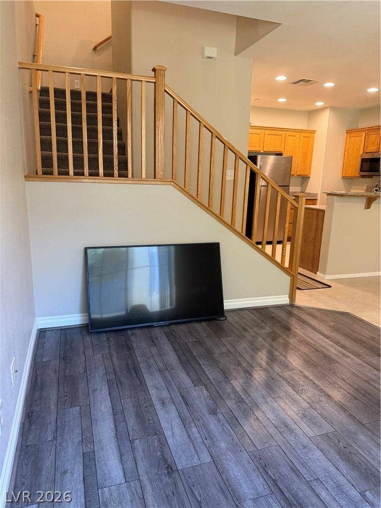 Rich wood plank flooring pairs seamlessly with a classic wood-rail staircase in this open layout.