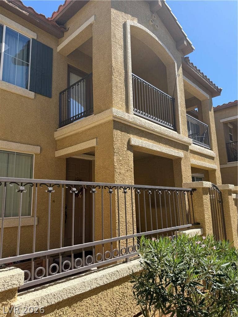 Stucco exterior walls pair with wrought iron railings under a sunny blue sky.
