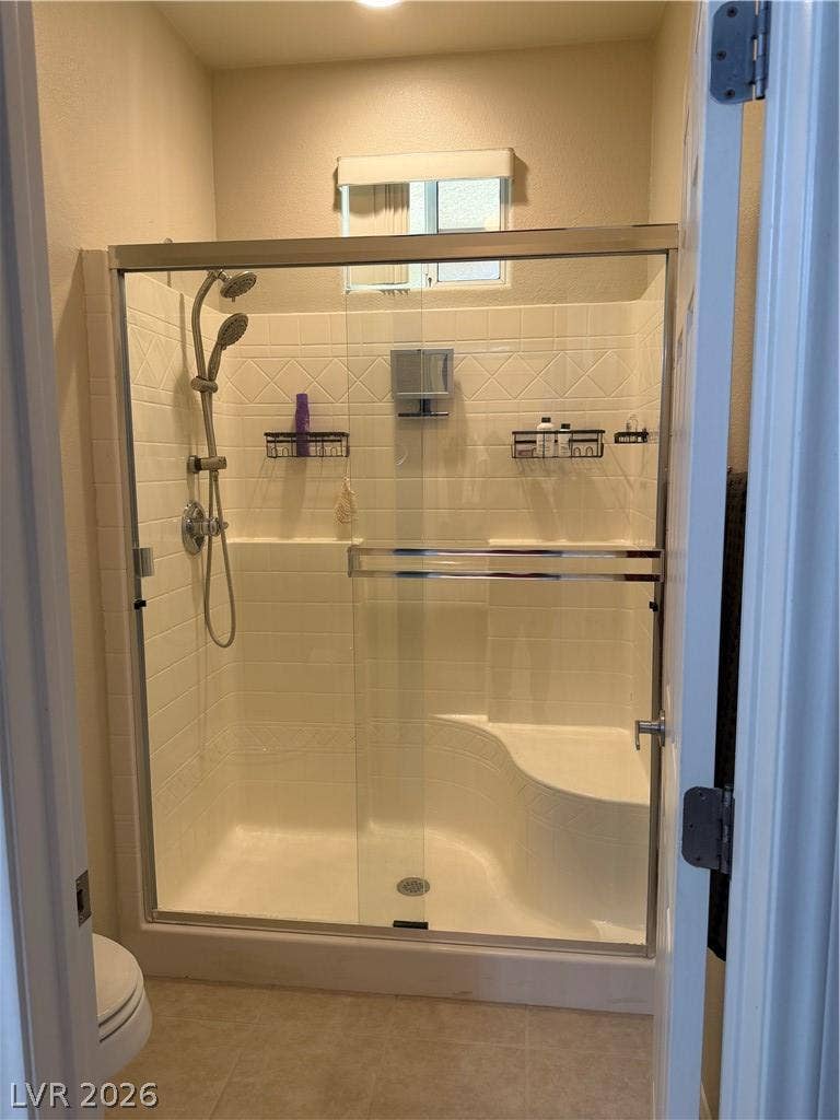 Tiled walk-in shower features glass doors and integrated seating.