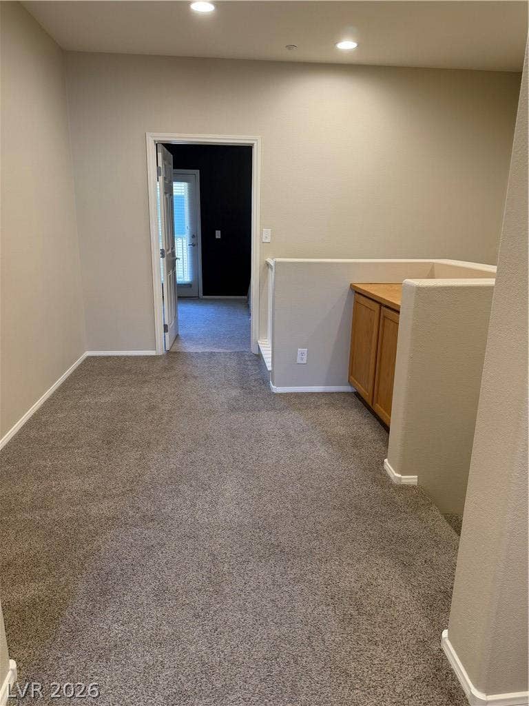 A functional landing area features plush carpeting, recessed lighting, and convenient built-in storage cabinetry.