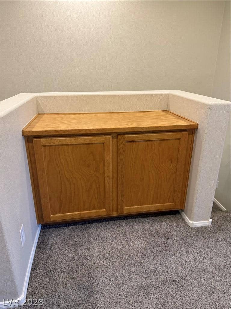 A built-in wooden storage cabinet sits seamlessly alongside the carpeted staircase landing.