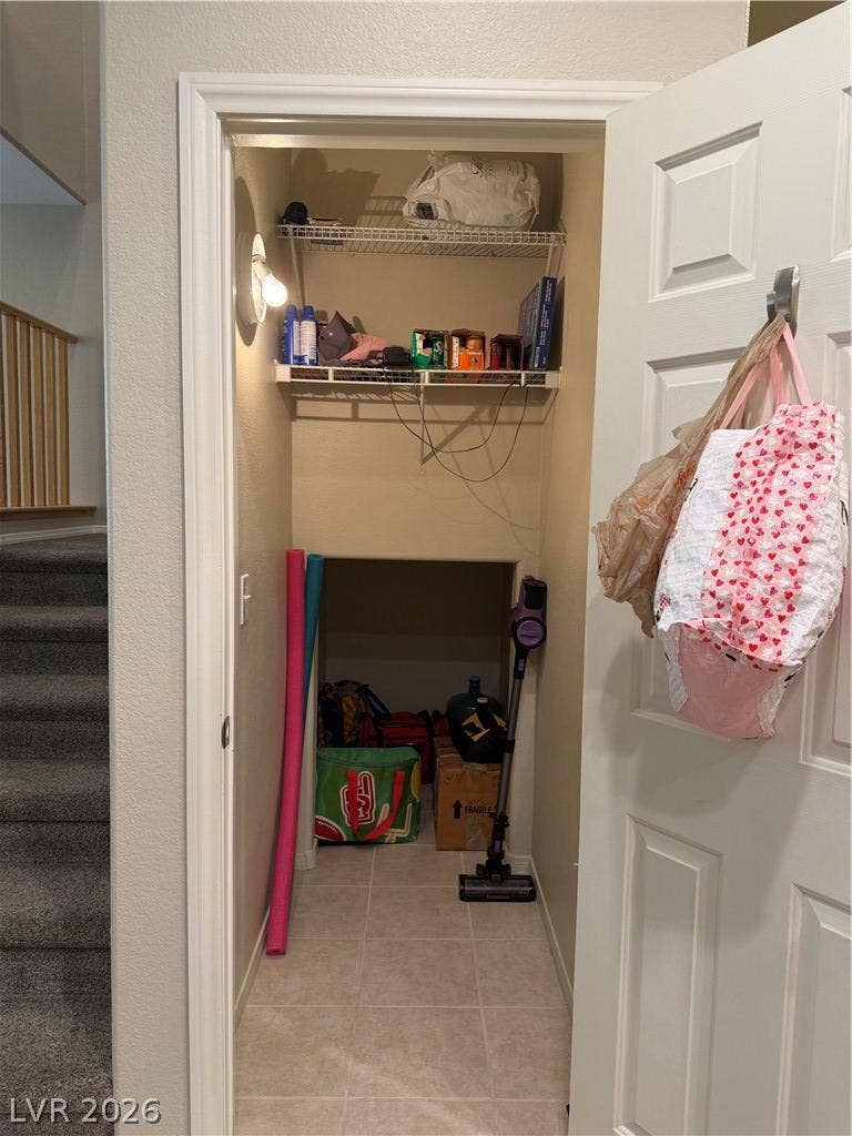Tiled storage closet beneath the stairs provides practical home organization.