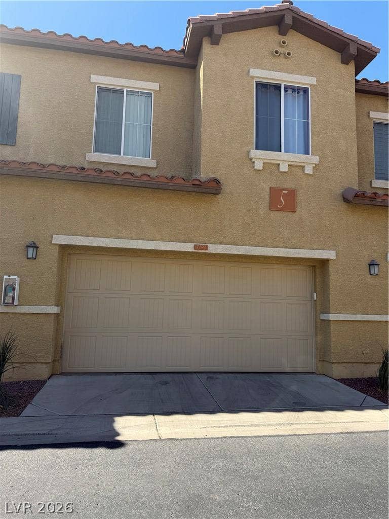 Stucco exterior elements pair with a tiled roof above the integrated multi-car garage.