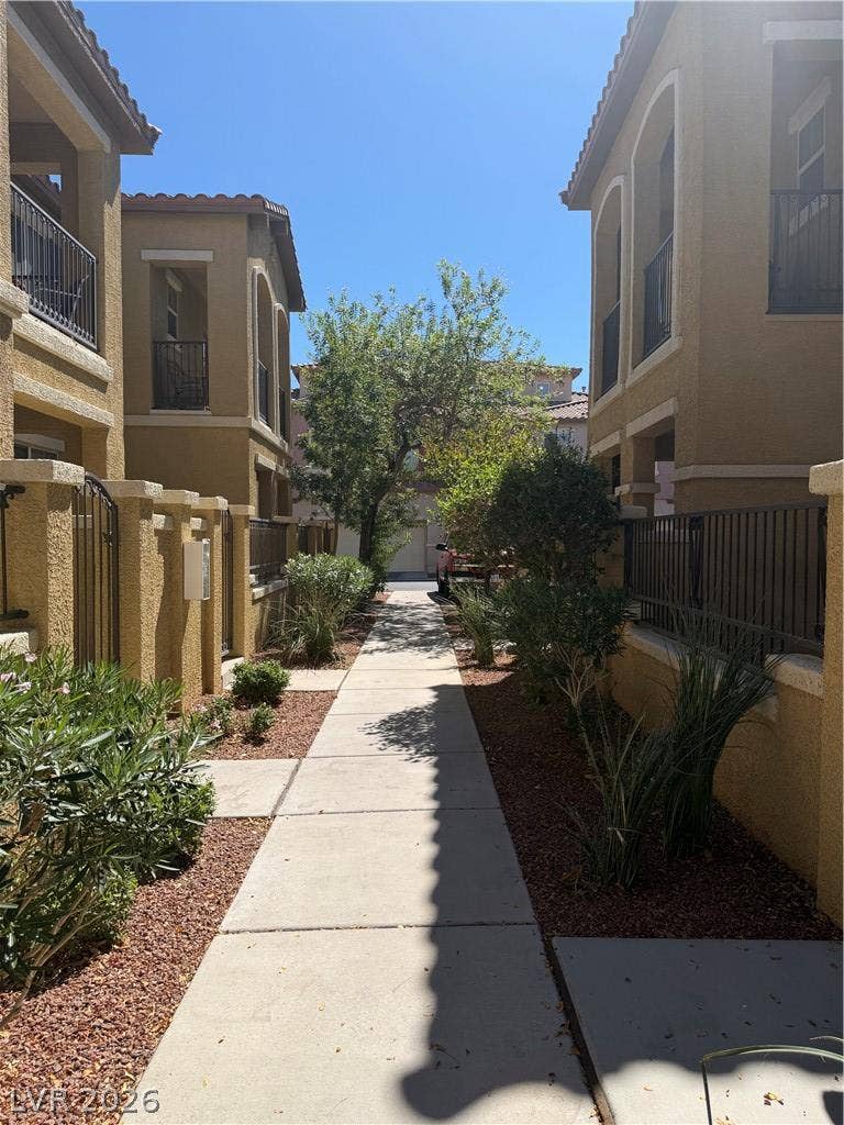 Concrete walkways meander between stucco structures under clear blue skies.