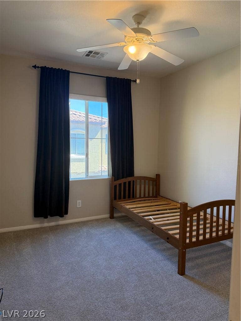 Natural light fills this bedroom featuring plush carpeting and a large multi-pane window.