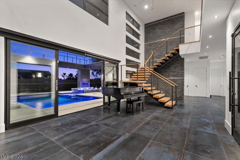 2839 Edgemont Drive, Henderson, NV 89074 A grand entrance with an open floor plan, featuring a striking modern staircase and sliding glass doors leading to a private pool.