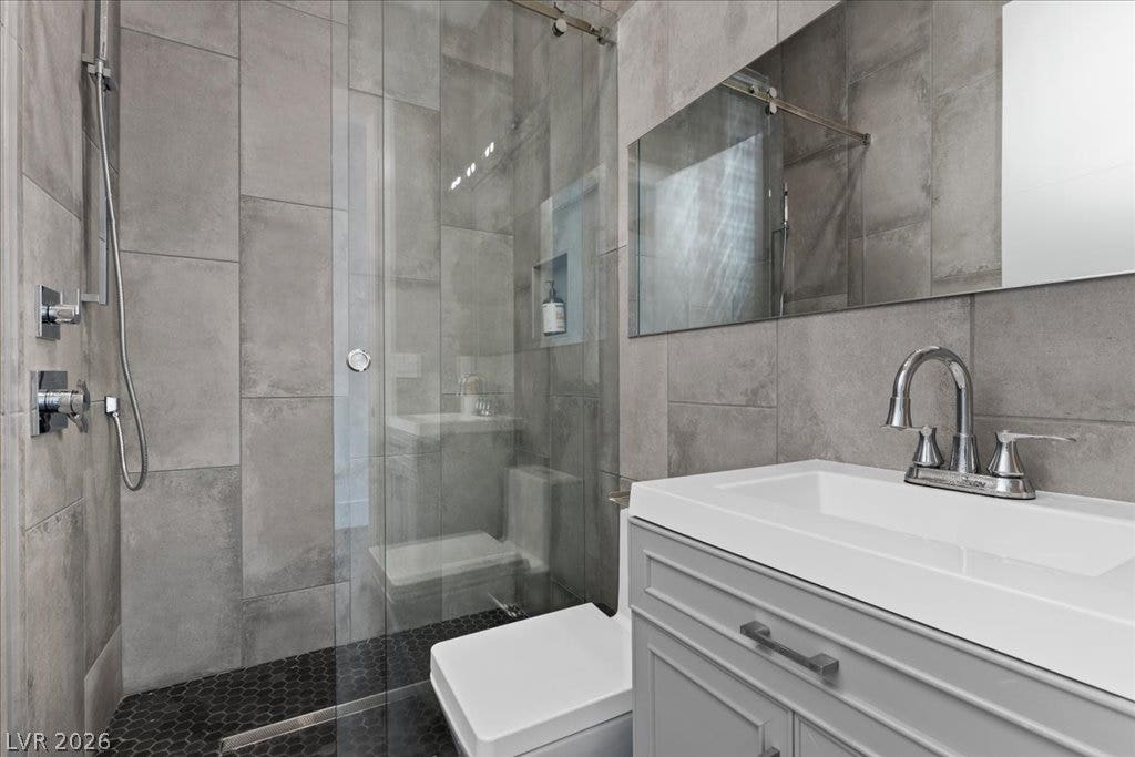 2839 Edgemont Drive, Henderson, NV 89074 Modern bathroom featuring sleek vanity, tiled walls, and a convenient glass-enclosed shower.