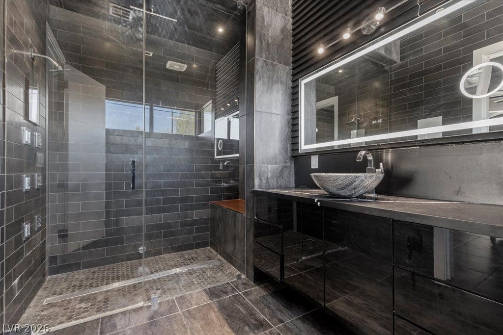 2839 Edgemont Drive, Henderson, NV 89074 Luxurious bathroom with sleek dark tile and a contemporary vanity with illuminated mirror.