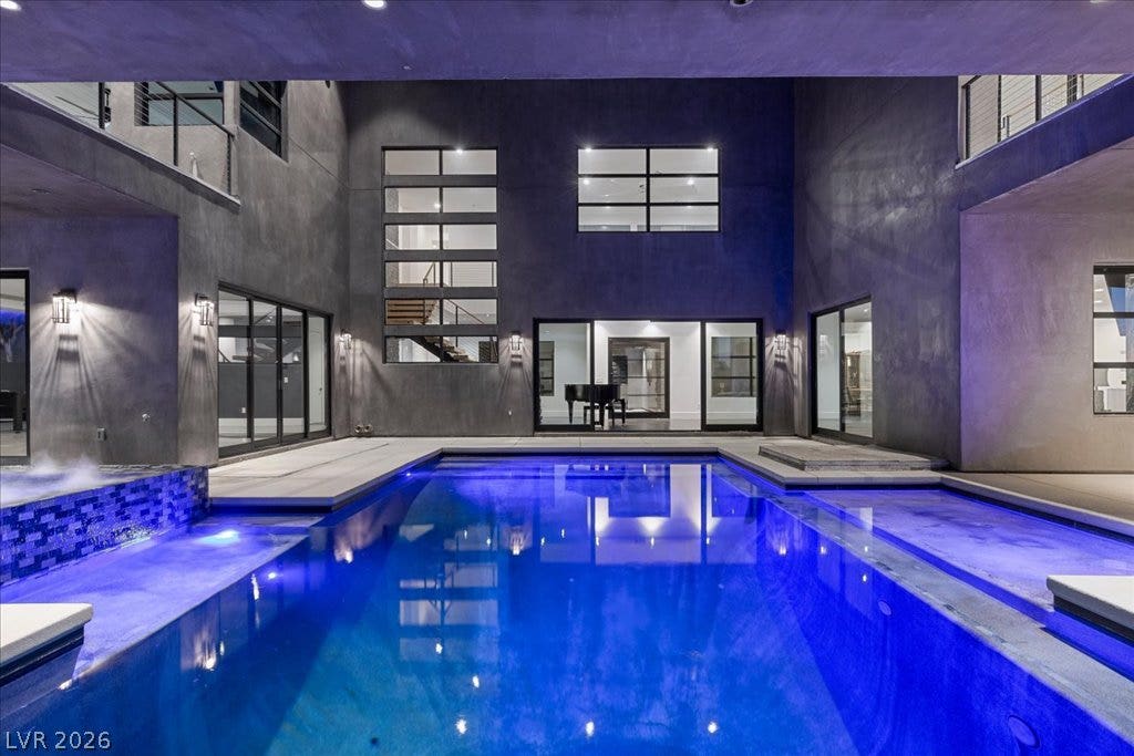 2839 Edgemont Drive, Henderson, NV 89074 An illuminated backyard pool with a hot tub and dark modern architecture creates a captivating evening retreat.