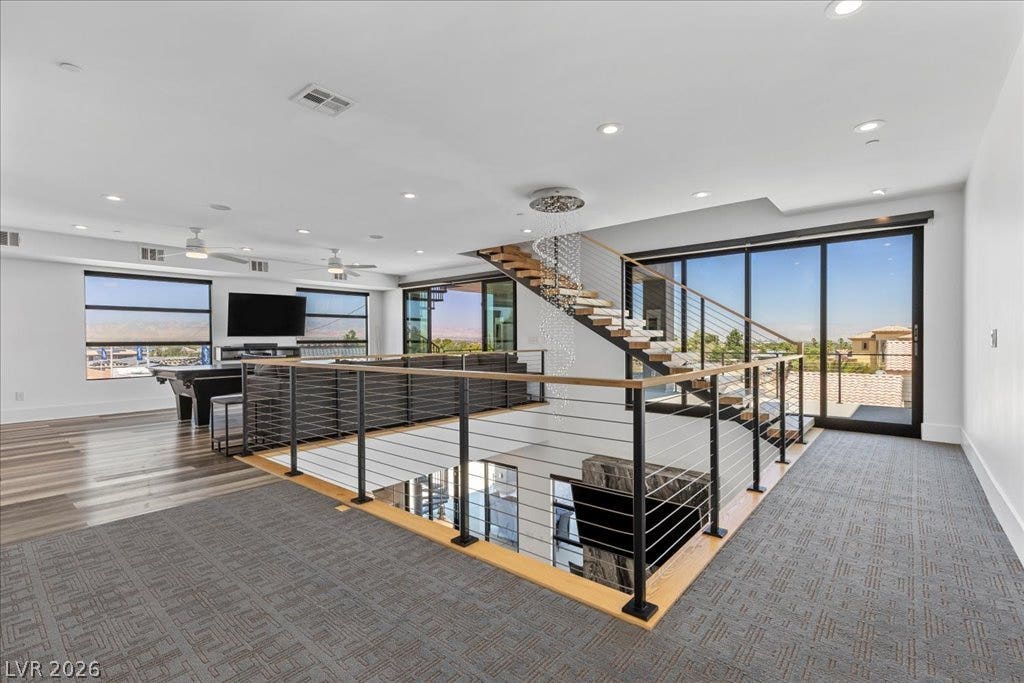 2839 Edgemont Drive, Henderson, NV 89074 A grand floating staircase and open-concept living area with extensive windows offer abundant natural light and sweeping views.