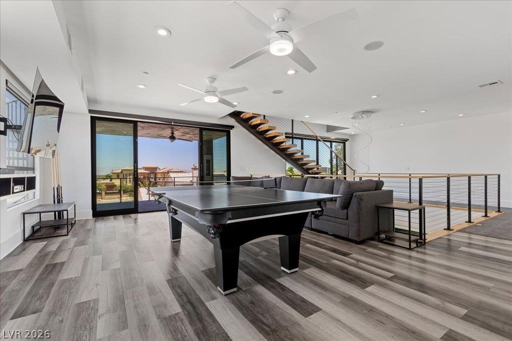 2839 Edgemont Drive, Henderson, NV 89074 A spacious game room offers ample space for entertaining and relaxation, featuring a modern staircase and large sliding glass doors.