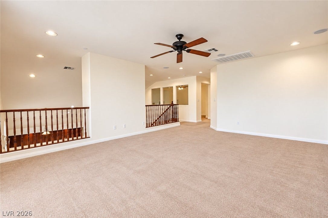669 Doubleshot Lane, Henderson, NV 89052 A spacious upper-level loft features wall-to-wall carpeting and open wooden railings overlooking the stairs.
