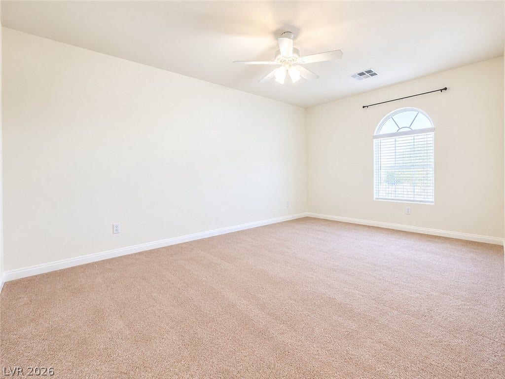 669 Doubleshot Lane, Henderson, NV 89052 A spacious bedroom features soft neutral carpeting and an elegant arched window.